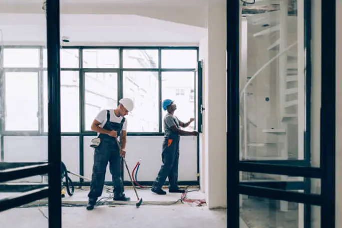 Baustellenreinigung mit Vakuumgeräten durch einen männlichen Arbeiter in staubiger Umgebung